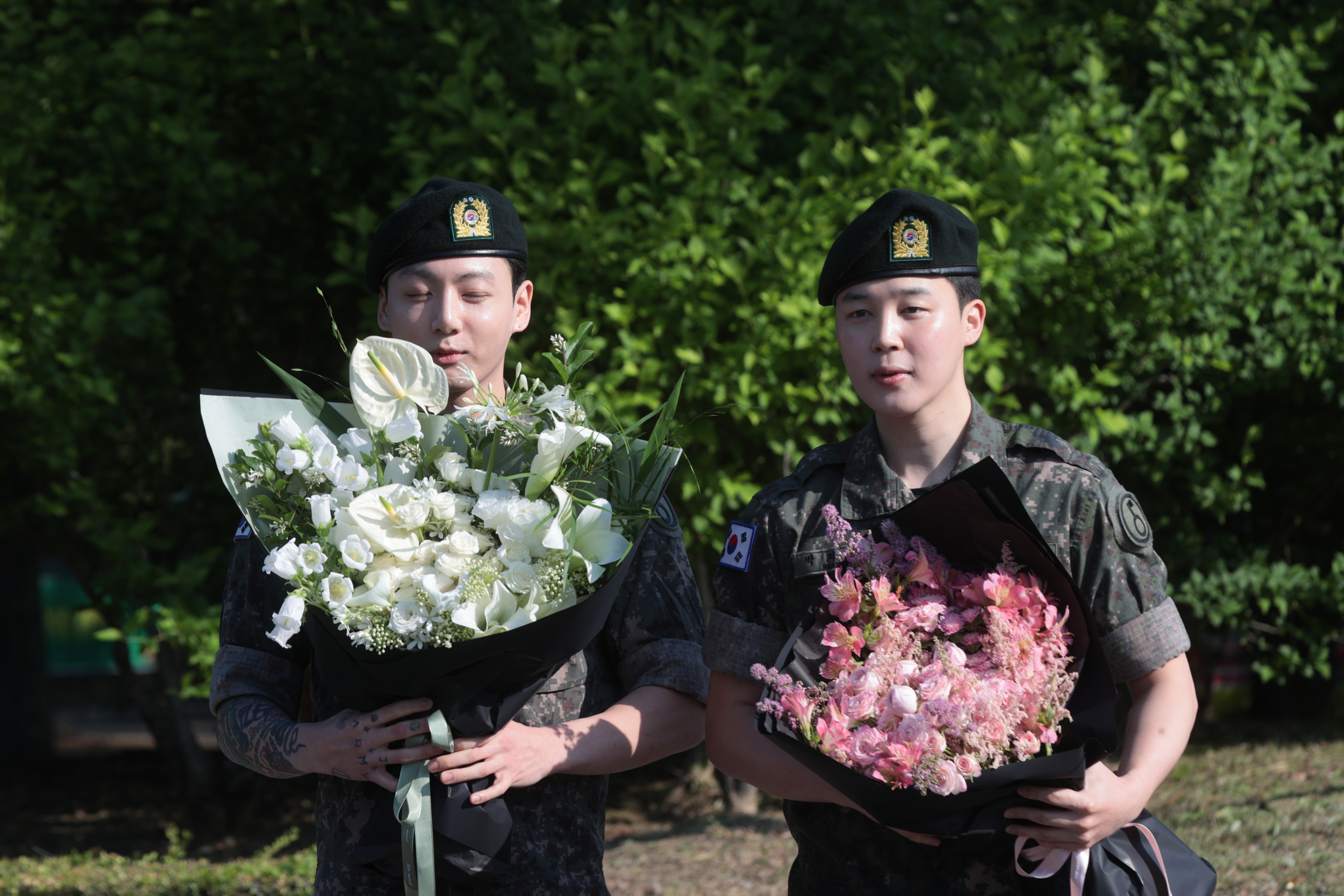 Members Jungkook, left, and Jimin of boy band BTS greet reporters with flower bouquets in their hands, after finishing their military duties on June 11 in Yeoncheon, Gyeonggi. [YONHAP]