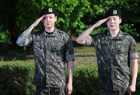 Members Jungkook, left, and Jimin of boy band BTS salute fans after finishing their military duties on June 11 in Yeoncheon, Gyeonggi. [NEWS1]
