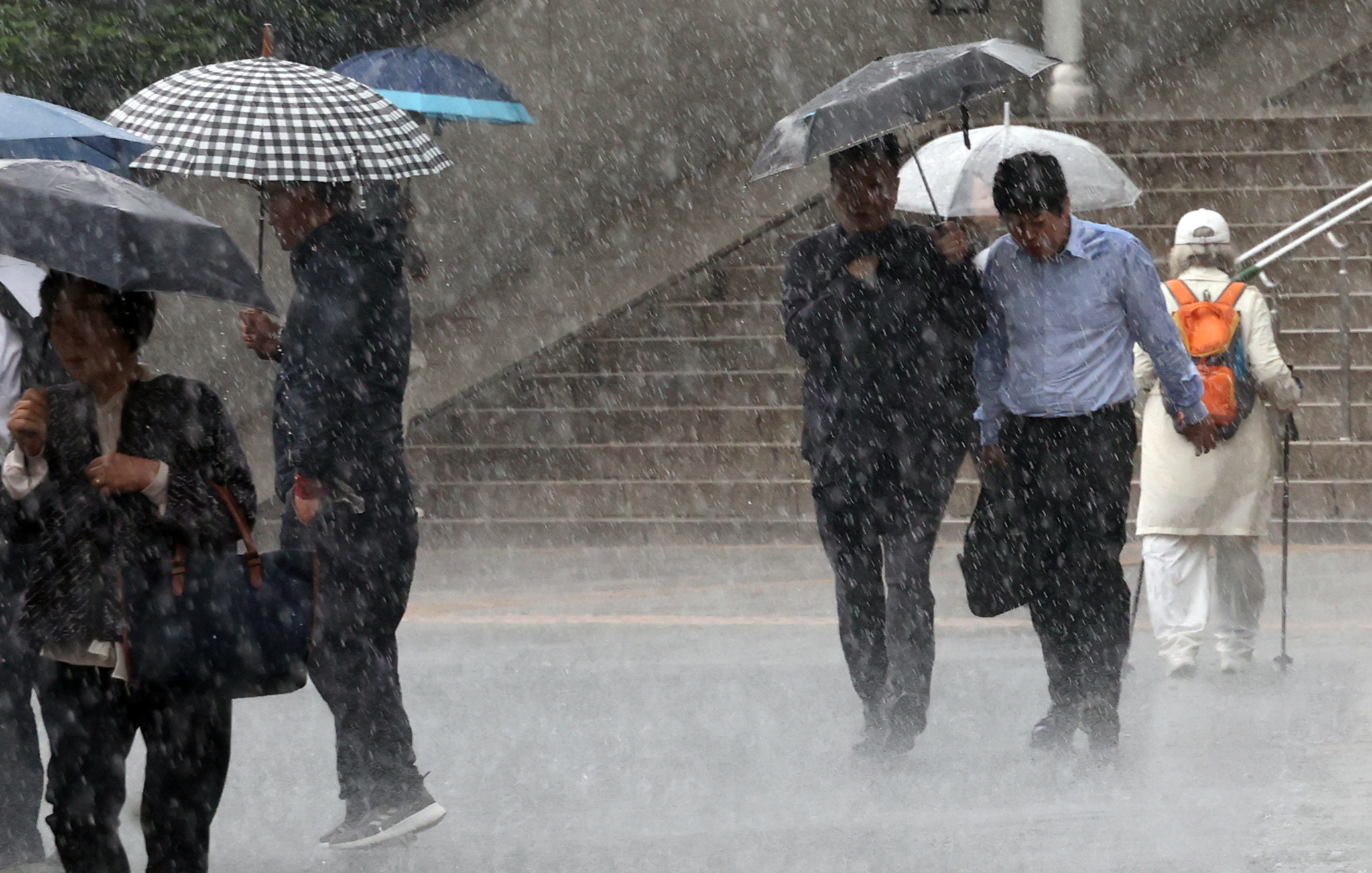 Heavy rain hits pedestrians walking by Seoul Station in Jung District, central Seoul, on May 16. [YONHAP] 