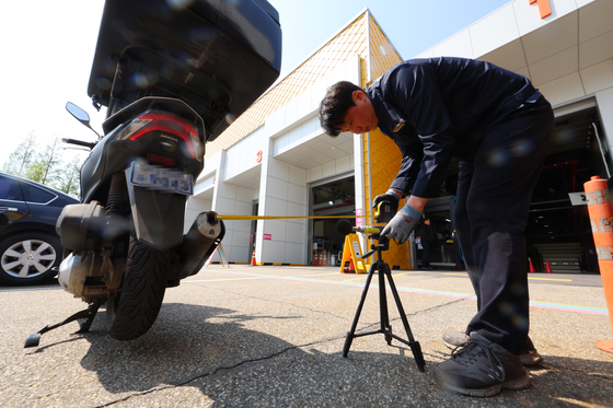 A motorcycle is being checked on April 28 in western Seoul. The license plate is stuck at the rear end of the vehicle. [YONHAP]
