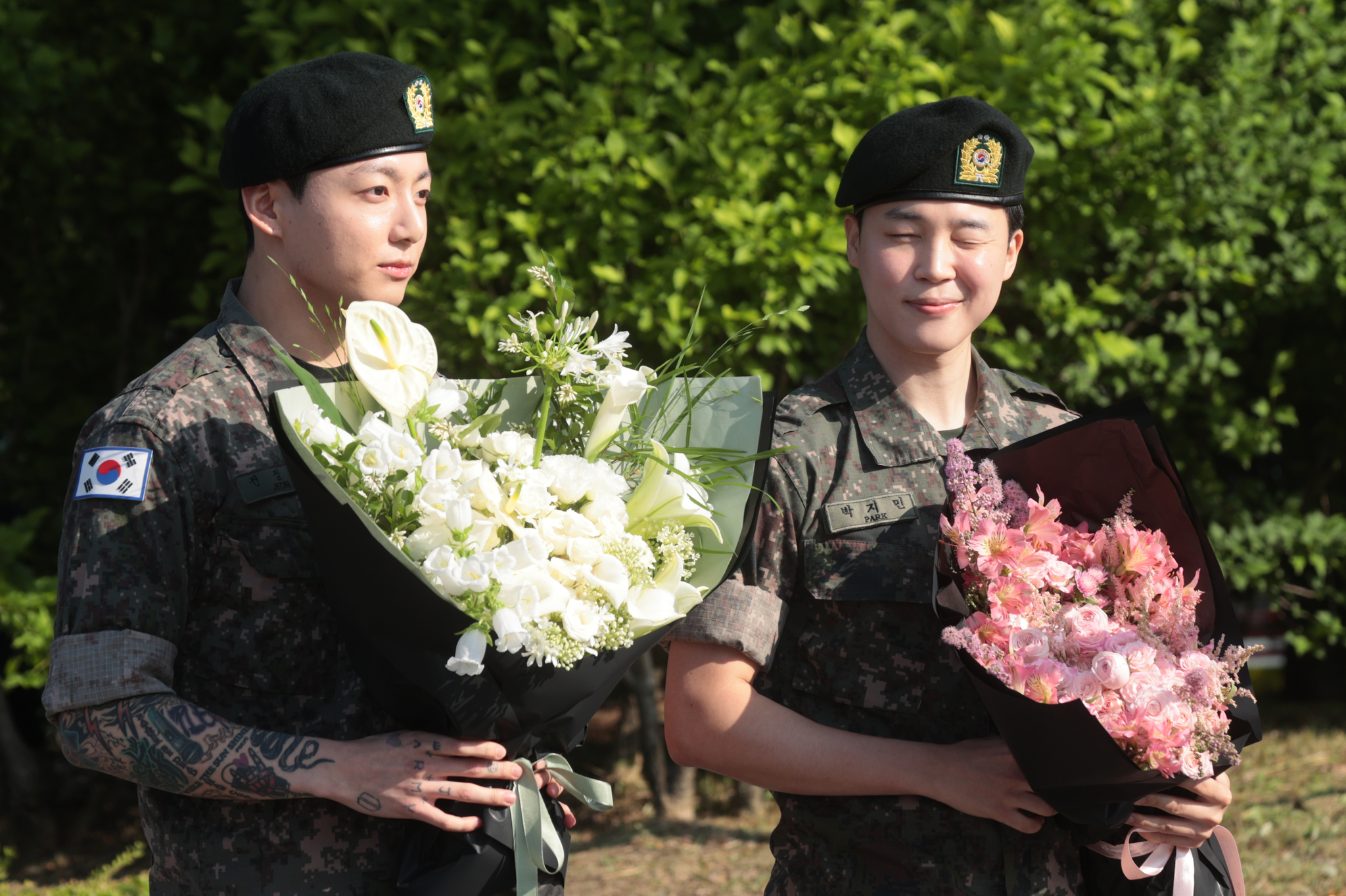 Members Jungkook, left, and Jimin of boy band BTS greet reporters with flower bouquets in their hands, after finishing their military duties on June 11 in Yeoncheon, Gyeonggi. [YONHAP]