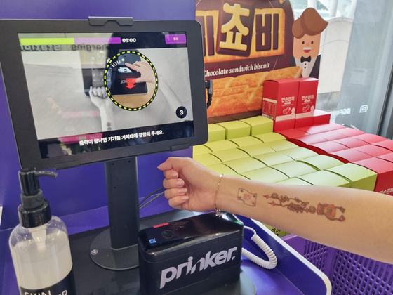 A temporary tattoo is applied to a customer's inner forearm at a CU convenience store in Seoul. [BGF RETAIL]