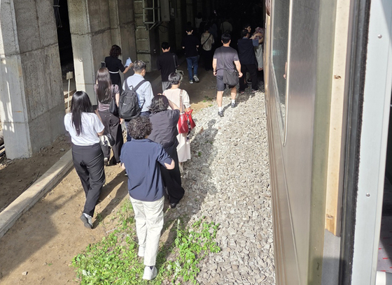 Passengers walk along the tracks after a crane truck accident halts the Gyeongui–Jungang Line service on the morning of June 13. [NEWS1] 