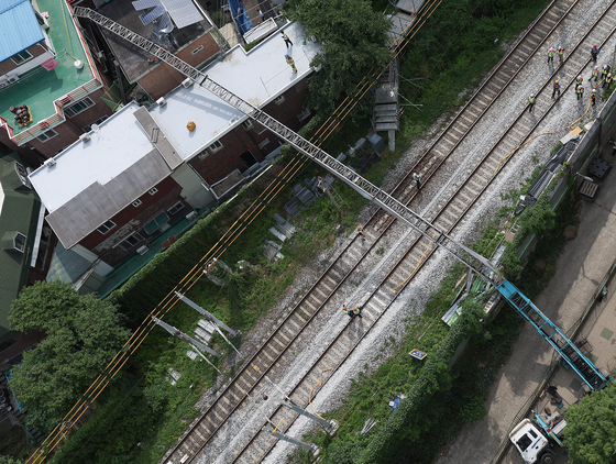 A ladder truck collapses over the tracks between Gajwa Station and Sinchon Station on Gyeongui-Jungang line in western Seoul on Friday morning, suspending and delaying train operations. [YONHAP] 