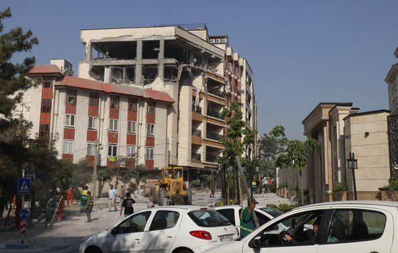 Onlookers watch as rescue teams clear the rubble in front of a building targeted by an Israeli strike in the Iranian capital Tehran on June 13. [AFP/YONHAP] 