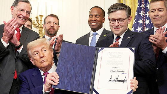 U.S. President Donald Trump shows a signed resolution approved by Congress to rescind the EPA's 2023 approval of California's plans to require a rising number of zero-emission heavy-duty trucks, and another resolution on California's low-NOx, or low-nitrogen oxide, regulation for heavy-duty highway and off-road vehicles and engines, at the White House in Washington on June 12. [REUTERS/YONHAP]