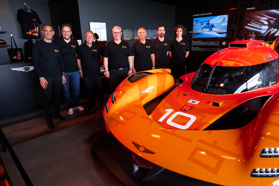 Members of the Genesis Magma Racing team pose in front of the GMR-001 hypercar at the Genesis booth during the 24 Hours of Le Mans endurance race in France on June 13. [HYUNDAI MOTOR GROUP] 