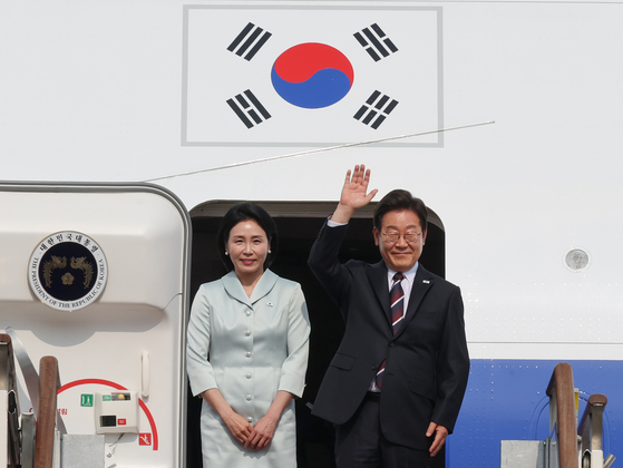 President Lee Jae-myung, right, and first lady Kim Hye-kyung greet onlookers at Seoul Air Base in Seongnam, Gyeonggi, before boarding the presidential jet bound for Canada on June 16. [YONHAP] 