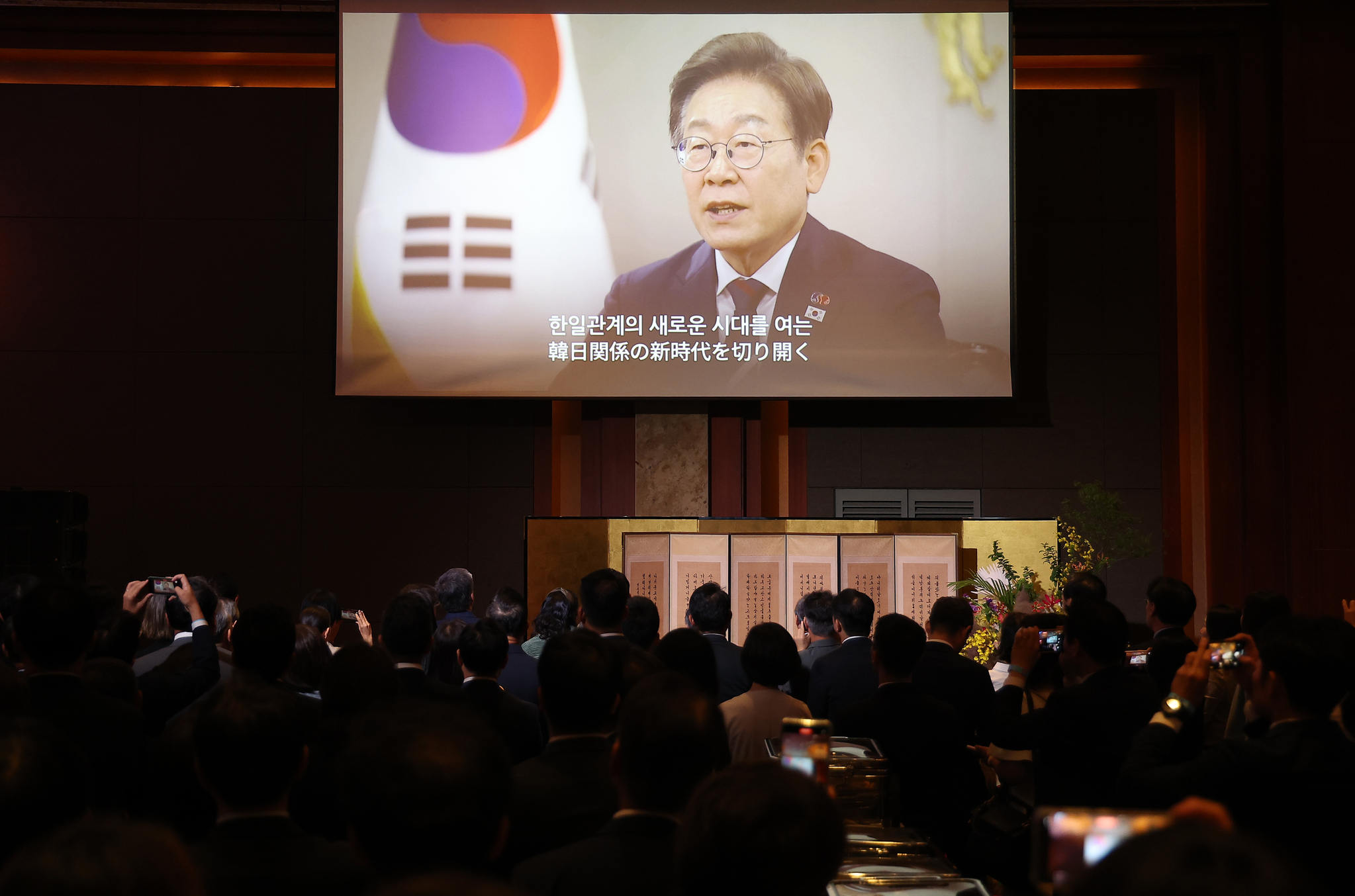 President Lee Jae Myung delivers a congratulatory video message marking the 60th anniversary of Korea-Japan diplomatic normalization at a ceremony held Monday afternoon at the Lotte Hotel Seoul. [YONHAP]