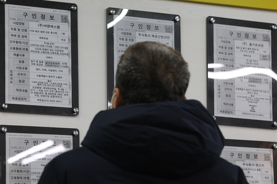 A job seeker looks at job opening notices at an employment center in Seoul on March 12. [YONHAP] 