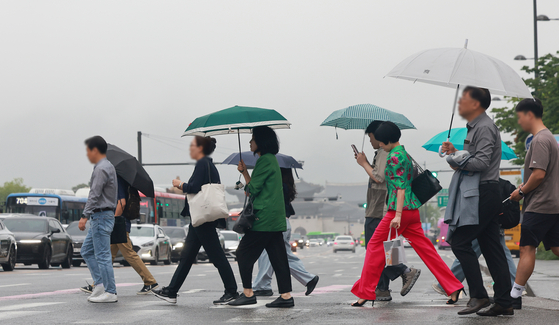 Pedestrians with umbrellas cross Sejong-daero, a street in Jongno District, central Seoul, on June 16 as rain pelts the country. [YONHAP]
