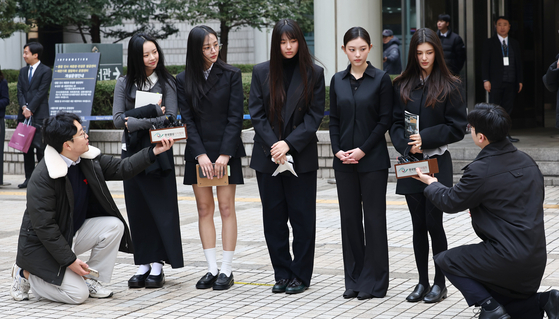 Members of girl group NewJeans take questions from reporters at the Seoul Central District Court building in southern Seoul on March 7 after taking part in a lawsuit against their agency, ADOR. [YONHAP]