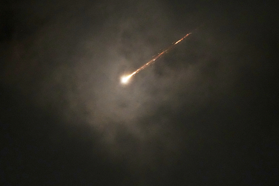The trail of a projectile is seen through the clouds following a missile alert after launches from Iran, in Jerusalem, early Monday, June 16, 2025. [AP/YONHAP]