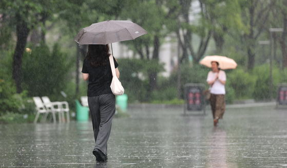 People hold umbrellas as they walk in central Seoul on June 20. [NEWS1]