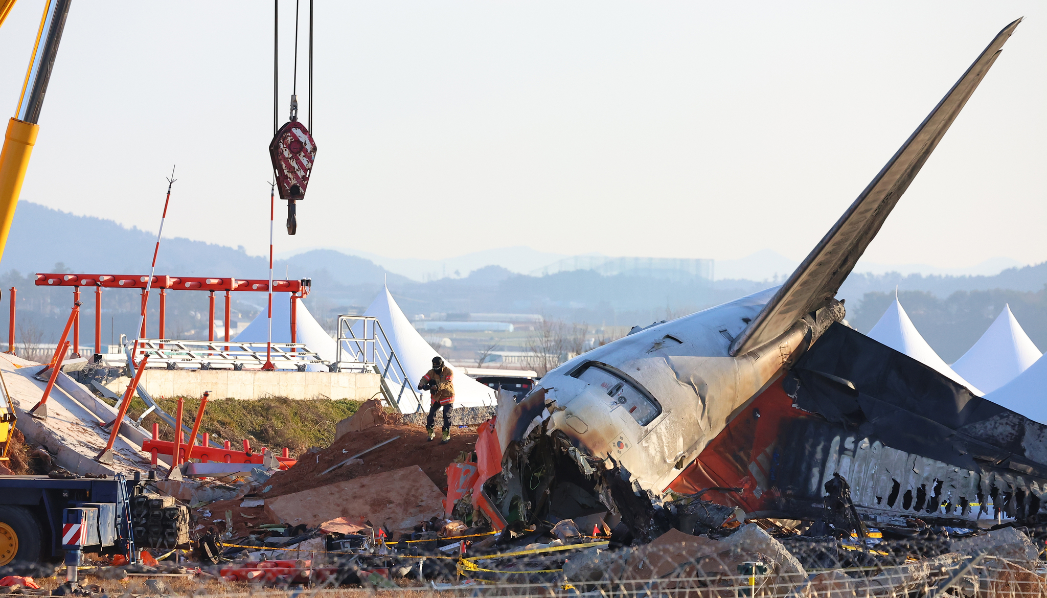 Fire authorities inspect a site where Jeju Air's Boeing 737-800 aircraft was collided with the concrete embankment six days ago at Muan International Airport in South Jeolla. [YONHAP]