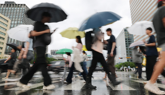 Pedestrians hold umbrellas as they cross a road in central Seoul on the morning of June 20. [NEWS1]
