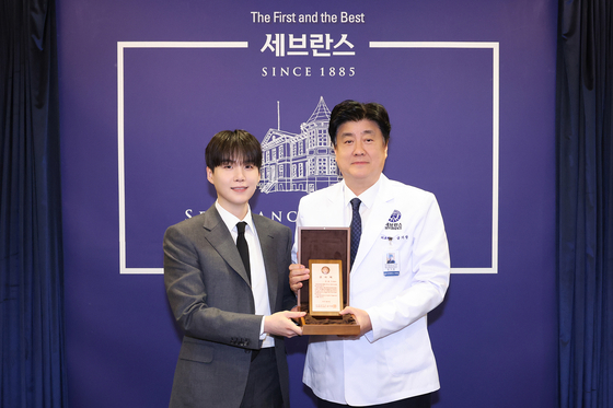 Suga of boy band BTS poses for photos with Keum Ki-chang, president and CEO of Yonsei University Health System, at the Severance Hospital in western Seoul. [SEVERANCE]