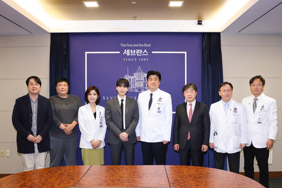 Suga of BTS, fourth from left, poses for photos with medical staff and researchers at Severance Hospital in western Seoul on June 23. [YONHAP] 