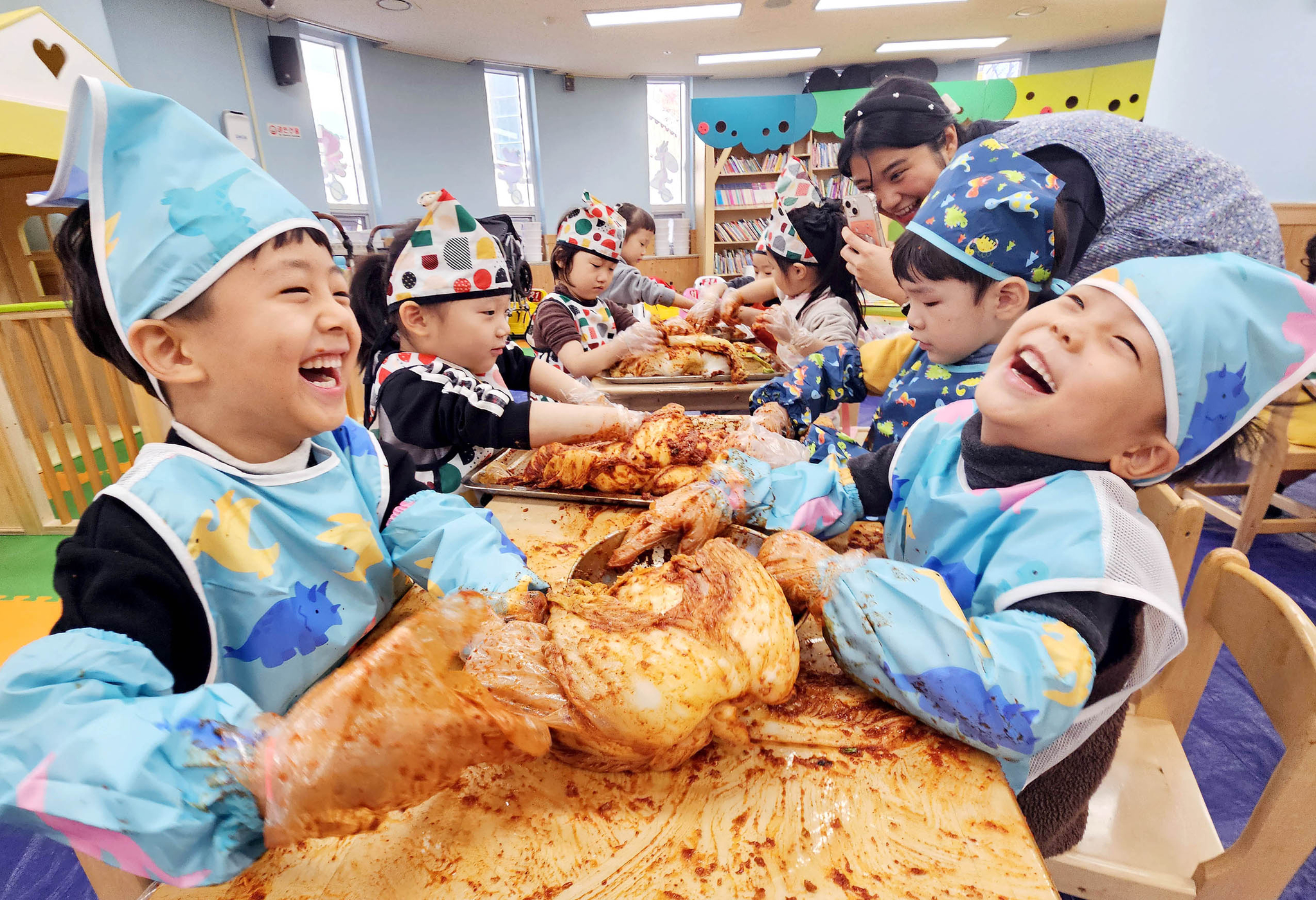 Children smile while making kimchi at their day care center in Gwangju in December 2023. [YONHAP] 