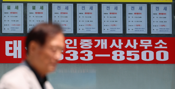 A passerby walks past a real estate agency displaying rental listings in Seoul on June 23 as the city undergoes a sharp rise in housing prices. [YONHAP]