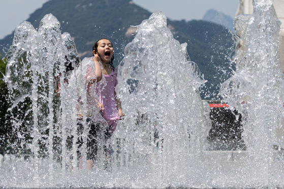 Children cool off in the ground fountain at Gwanghwamun Square in central Seoul on June 23, as temperatures soar to a daytime high of 32 degrees Celsius. [NEWS1] 