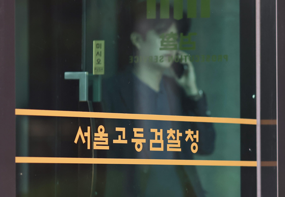 A person talks on the phone behind the doors of the Seoul High Prosecutors’ Office in Seocho District, southern Seoul, where the special counsel team investigating the martial law allegations is based, on June 26. [YONHAP]