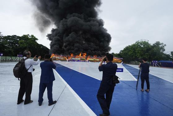 Journalists take photos of burning illegal narcotics during a destruction ceremony to mark International Day against Drug Abuse and Illicit Trafficking, on the outskirts of Yangon, Myanmar, June 26. [AP/YONHAP]