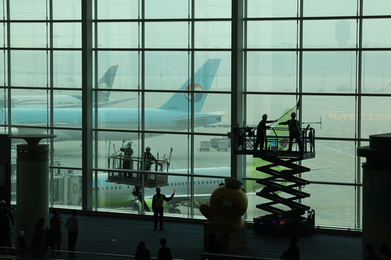 Staff clean the windows of Incheon International Airport on March 25. [YONHAP]
