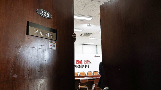 A People Power Party official closes the doors to the party's meeting room at the National Assembly in Yeouido, western Seoul after an emergency commitee meeting was canceled on June 5. [LIM HYUN-DONG]