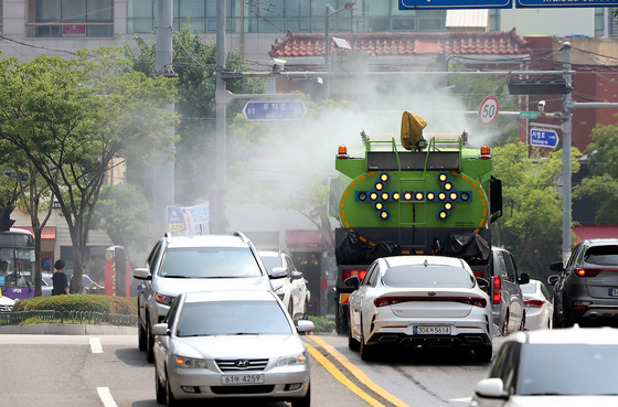 Sprinkler vehicles spray roads with water to cool off the pavement in Buk District in Gwangju on June 26. [NEWS1]