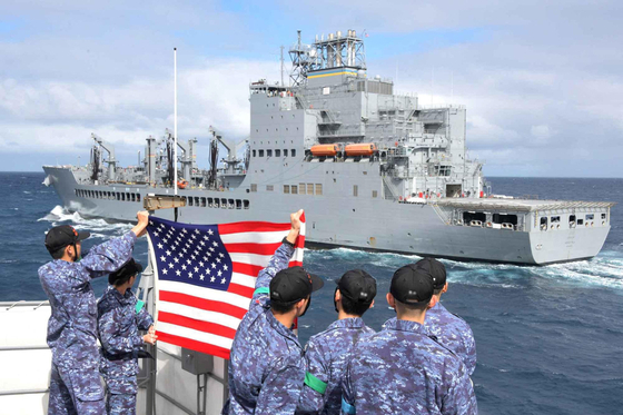 Crewmembers of the Japanese Maritime Self-Defense Force's JS Shimakaze guided missile destroyer hold a U.S. flag toward the U.S. Navy's USNS Harvey Milk oiler during an exercise in the Virginia Capes’ operating area in the Atlantic Ocean on Sept. 24, 2024, in this photo provided by the U.S. Navy. [REUTERS/YONHAP] 