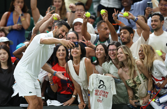 Serbia's Novak Djokovic poses for selfies with spectators after winning his first round match against France's Alexandre Muller on July 1. [REUTERS/YONHAP]