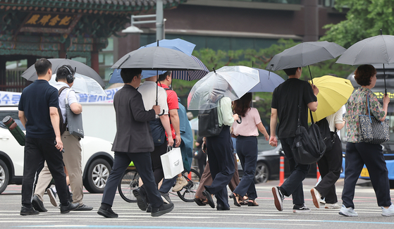 Citizens cross a street near Gwanghwamun Square in Jongno District, central Seoul in the rain on June 16. [NEWS1]