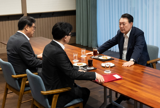 Former President Yoon Suk Yeol, right, sits down for a meeting with then-People Power Party leader Han Dong-hoon, center, on Oct. 21, 2024. [PRESIDENTIAL OFFICE]