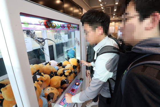 Young men play with a claw machine on April 11, 2017. [JOONGANG ILBO]