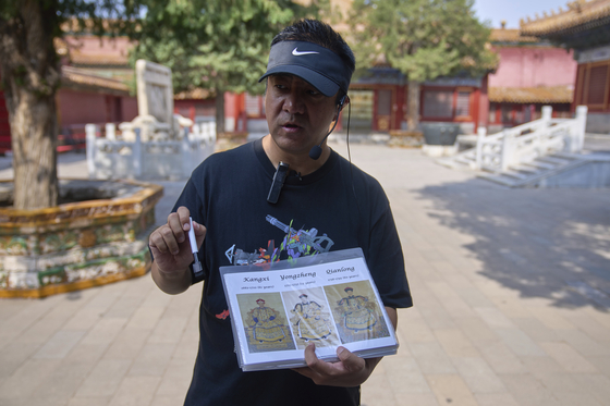 Tour guide Jim holds a paper displaying pictures of Chinese emperors as he trains a group of tour guides transitioning from Chinese-only to English tours at the Forbidden City in Beijing on June 18. [AP/YONHAP]