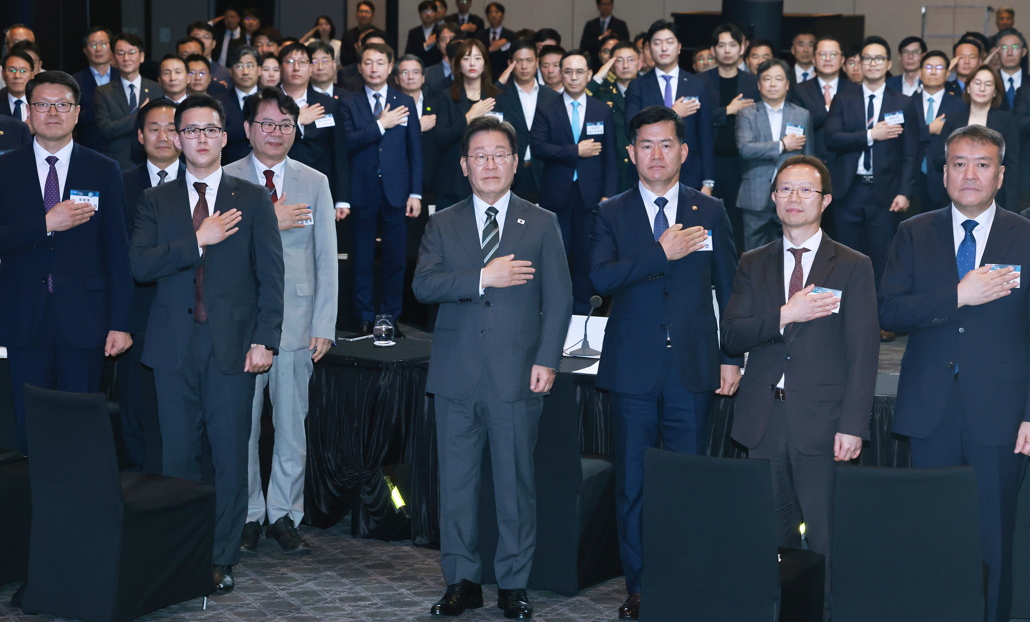 President Lee Jae Myung, center front, salutes the flag at an event to commemorate the inaugural K-Defense Day, flanked by aides and defense industry representatives and officials at a hotel in central Seoul on July 8. [JOINT PRESS CORPS]