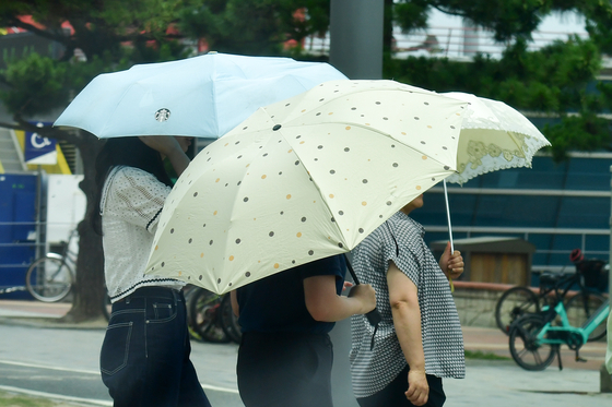 Tourists cross a sidewalk near a beach in Pohang on July 8. [NEWS1]