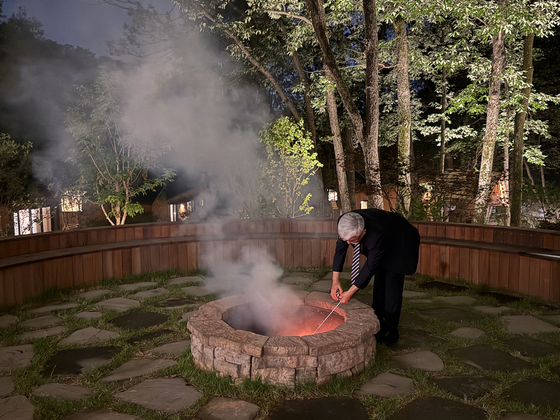 A hotel staffer revives a fire using a torch at one of Surak Hyu's three fire pits in Nowon District in northern Seoul on June 28. [LEE SOO-JUNG]