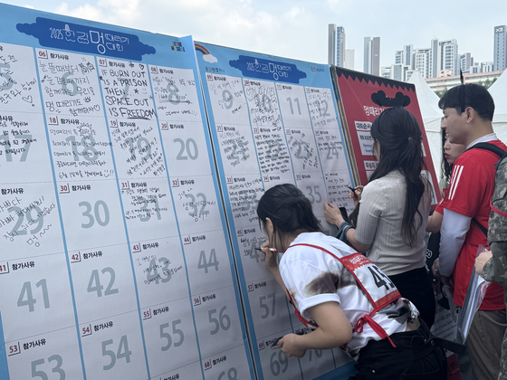 Contestants write their reasons for participation ahead of the Hangang Space-out Competition near Jamsu Bridge in Seocho District, southern Seoul, on May 11. [CHO JUNG-WOO]