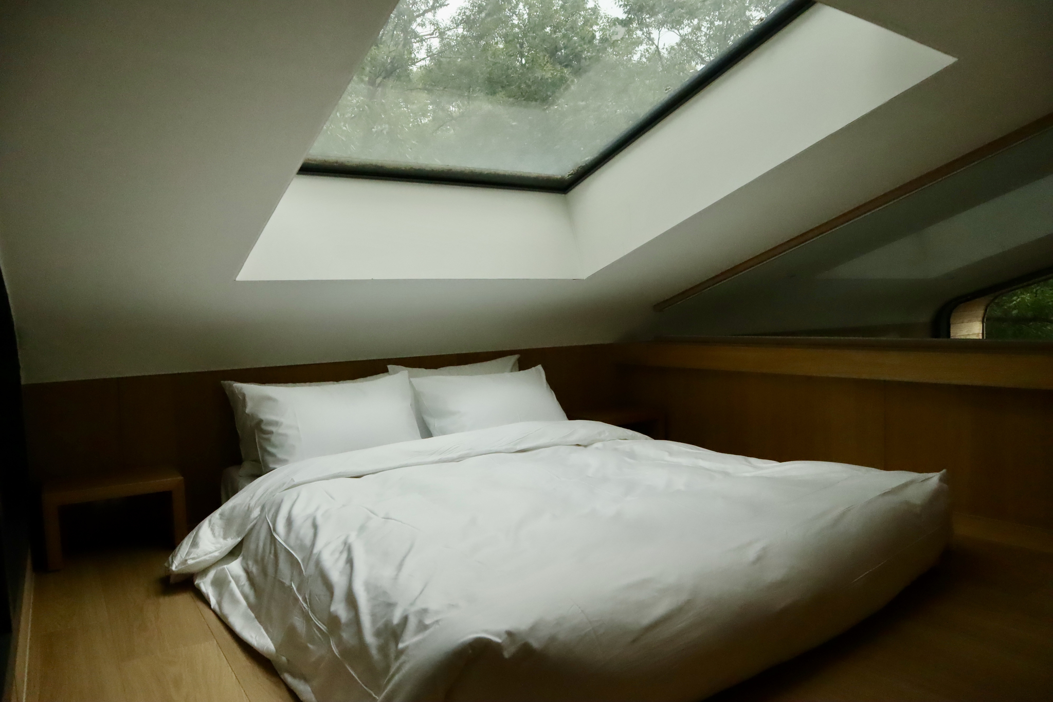 A queen-sized bed is on the loft inside a tree house at wellness village, Surak Hyu, in Nowon District in northern Seoul on June 28. The skylight window projects sunlight directly onto the bed. [LEE SOO-JUNG]