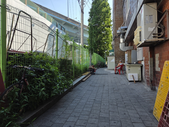 A resident of a jjokbang (tiny subdivided room) village rests in the shade in Yeongdeungpo District, western Seoul [SHIN HYE-YEON]