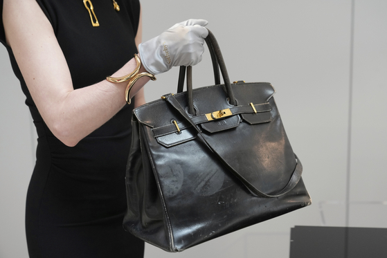 An auction officer carries the original Birkin bag created by Hermes for Jane Birkin in 1984, prior to its auction in Paris on July 10. [AP/YONHAP]
