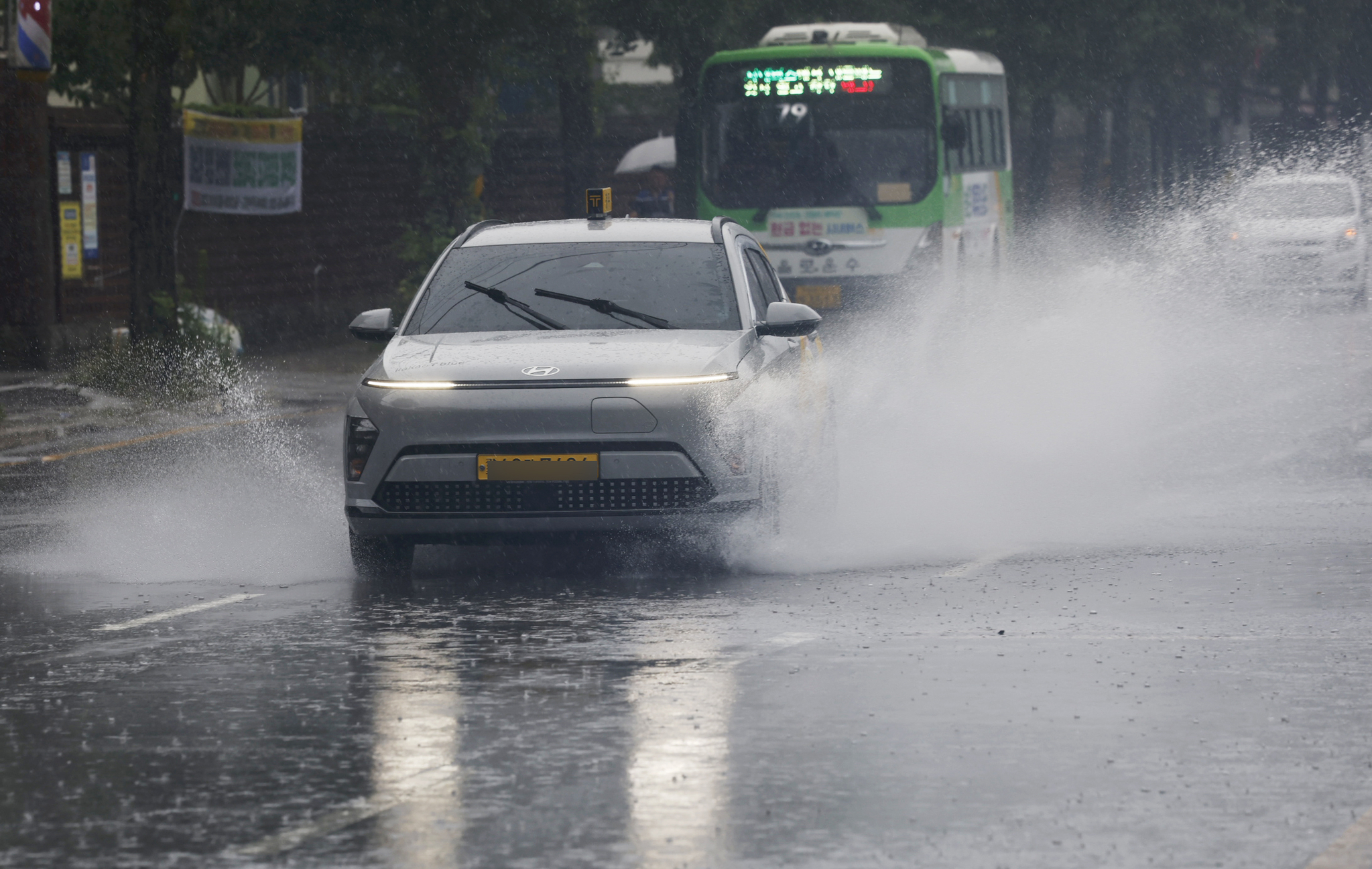 Vehicles cautiously drive through spray on a road beside the Gwangjucheon in Wolsan-dong, Nam District, Gwangju, as a heavy rain advisory is issued for parts of Gwangju and South Jeolla on July 13. [NEWS1] 