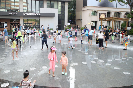 Children play in the fountains in Gwanghwamun Square during the Seoul Summer Beach festival in 2024. [SEOUL TOURISM ORGANIZATION]