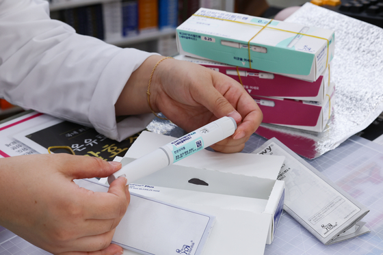 A pharmacist hands out the obesity treatment drug Wegovy at a pharmacy in Jongno District, central Seoul. [YONHAP]