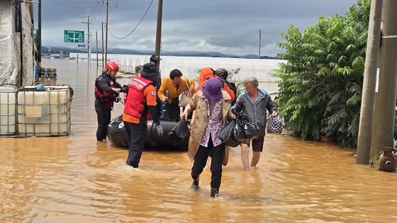Emergency workers use an inflatable boat to rescue residents stranded by floodwaters in Yesan County, South Chungcheong, on July 17. [SHIN JIN-HO]
