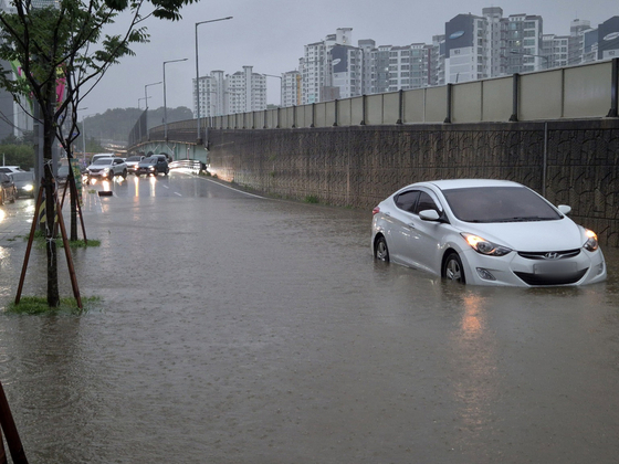 A car is stuck in a flooded road in Dangjin, South Chungcheong, on July 17. [DANGJIN CITY]