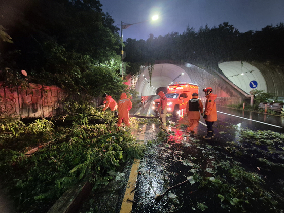 Firefighters and officials work to remove fallen trees off the streets of Bupyeong District, Incheon, on July 16. Trees fell due to landslides from the heavy rain, according to officials. [INCHEON FIRE DEPARTMENT]