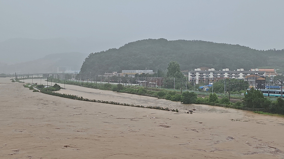 Water levels rise dangerously in a stream flowing through Sejong on July 17 as heavy rain pounds the area. A heavy rain warning was issued for Sejong at 1:12 a.m. that day. [YONHAP] 